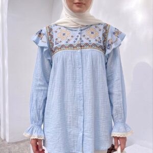 Front view of sky-blue crinkle-gauze blouse with geometric embroidered yoke and lace-trim ruffle sleeves.