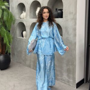Modelo con túnica satinada azul cielo con patrón mármol y pantalones palazzo, combinados con clutch adornado y tacones con lazo - Mayorista en Turquía