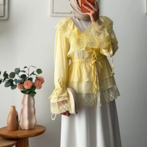 Front view of sheer yellow long-sleeve blouse with layered tiers, wide lace collar, and waist tie over a white skirt. available for wholesale in Turkey.