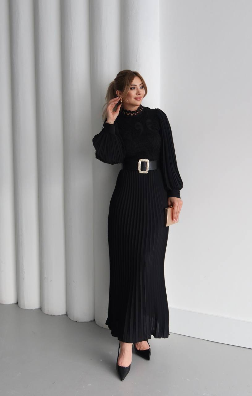schwarz-plissee-maxi-kleid-1926 – Großhandel Türkei Vollständige Ansicht eines plissierten schwarzen Maxikleids mit breitem dekorativem Gürtel und spitzen schwarzen Absätzen. Großhandel Türkei erhältlich.