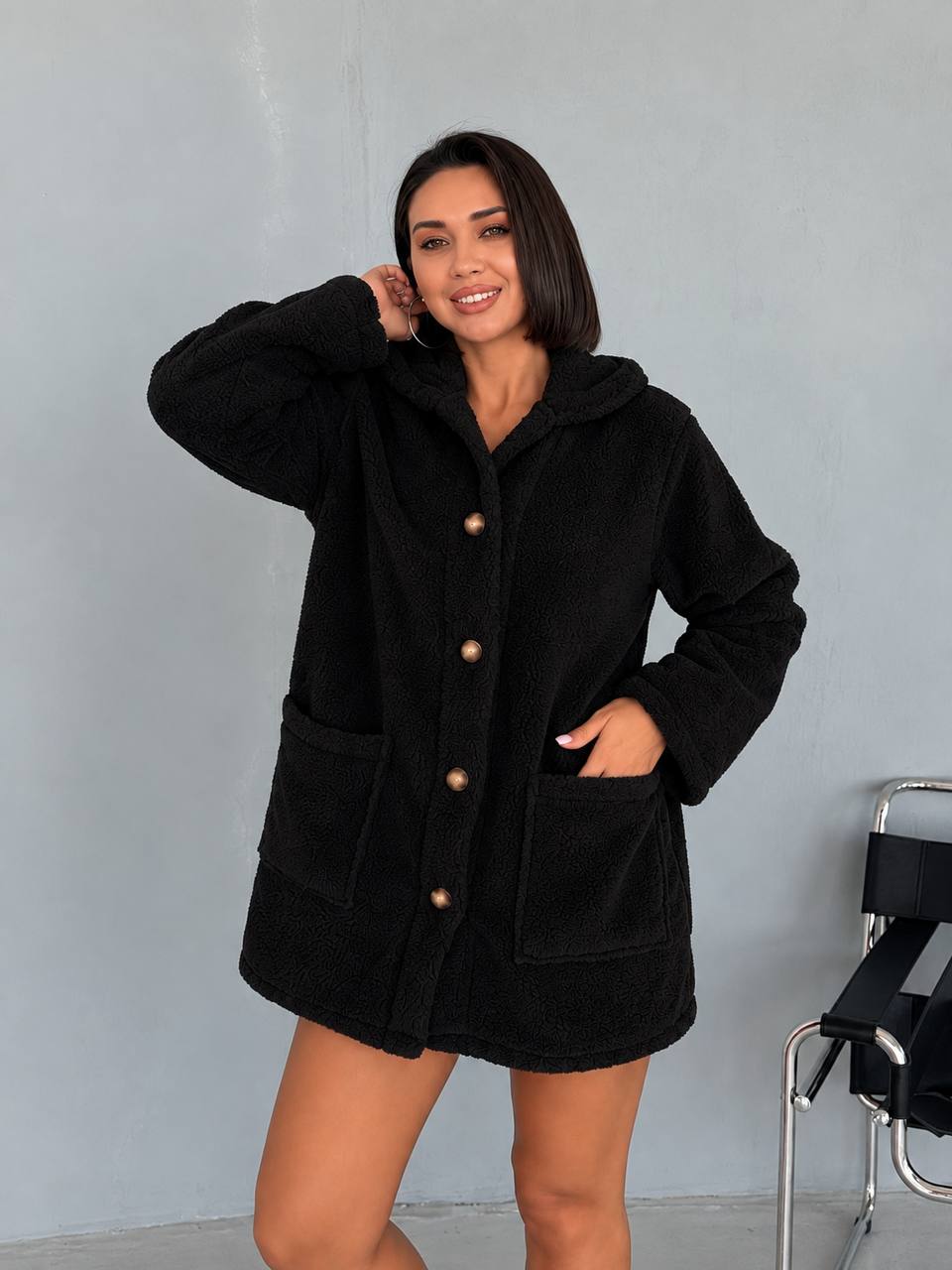 negro-abrigo-peluche-frente-7529 – Mayorista Turquía Abrigo negro con capucha, textura de pelaje, cuatro botones marrones, mangas largas y dos bolsillos delanteros grandes.