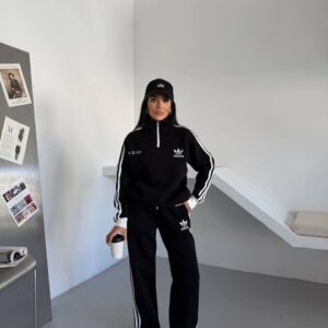 Full-length view of a black pullover tracksuit with a high collar and white side stripes.