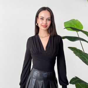 Black long-sleeve blouse featuring a deep V neckline, gathered shoulders, and a wide fitted waistband.