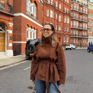 Woman wearing a brown high-neck jacket with button details, wide sleeves, and a tied waist belt. available for wholesale in Turkey.