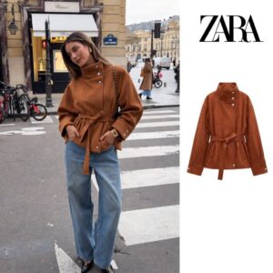 Brown jacket shown on a model and as a product view, featuring a high collar, silver buttons, and a waist belt.