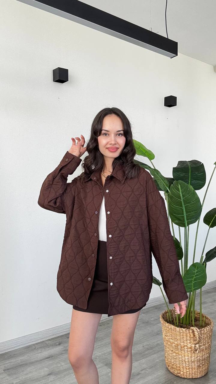 braun-gequiltete-overshirt-7509-Türkei-Großhandel Model trägt eine lange braune Jacke mit Knopfverschluss vorne, strukturierter geometrischer Steppung, spitzem Kragen und Brusttaschen - Türkei-Großhandel.