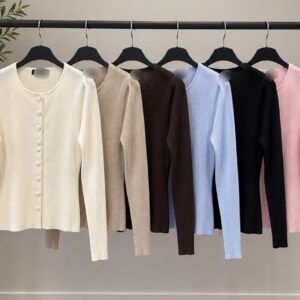 Seis cárdigan de canalé con botones frontales colgados de una percha en crema, beige, marrón, azul, negro y rosa. Turquía al por mayor.