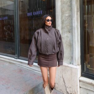 Model wears a charcoal oversized snap-front jacket with a dark denim mini skirt.