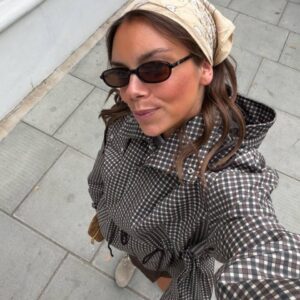 Overhead close-up of a gray checked jacket showing its hood, snap fasteners, and drawstring waist.