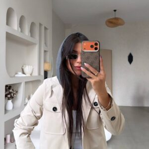 Cream jacket with black buttons, flap pockets, and a gray hood layered underneath.