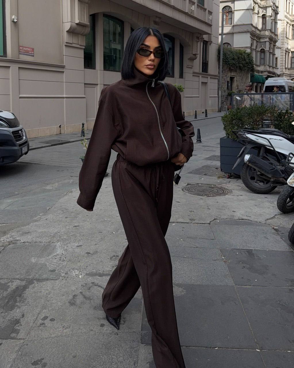 dark-brown-tracksuit-1753 A model wears a dark brown high-neck zip jacket with matching loose trousers.