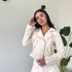 Front view of an ivory jacket with asymmetrical closure, zip pockets, snap lapels, and a buckled waist belt.