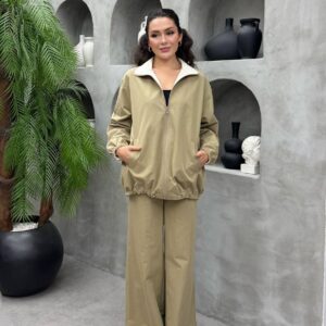 Model trägt khaki Reißverschluss-Jacke mit elastischem Kordelzug am Saum und passender weite Hose, Hände in den Taschen.