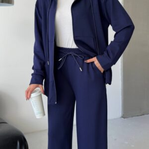 Vista frontal de una sudadera con capucha azul marino con cremallera abierta sobre una camiseta blanca, con pantalon de pierna ancha a la cintura con cordon. - Mayorista en Turquía