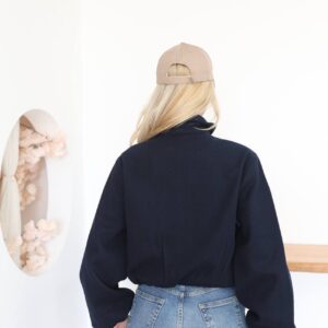 Back view of a navy cropped jacket with a plain panel, roomy sleeves, and a softly gathered hem.