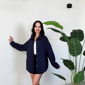 Full-length view of a navy quilted shirt jacket with a button front, worn over a white top and black skirt.