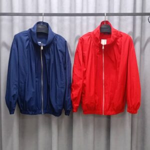 Chaquetas azul marino y roja colgadas lado a lado, cada una con cuello alto, cremallera frontal y dobladillo elástico. - Turquía Mayorista