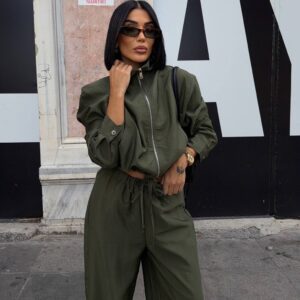 Closer view of an olive high-neck jacket with a central silver zipper and voluminous sleeves.