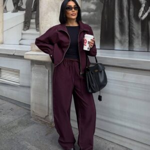 Front view of a plum jacket worn open over a black top with matching drawstring trousers.