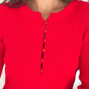 Close-up of red ribbed knit neckline showing vertical texture and six small round covered buttons along the placket.