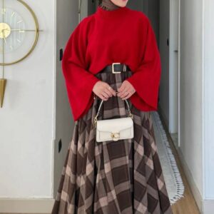 Model trägt einen roten Rollkragenpullover mit weiten Ärmeln, einen braunen karierten Maxirock und eine weiße Schultertasche. - Türkei-Großhandel