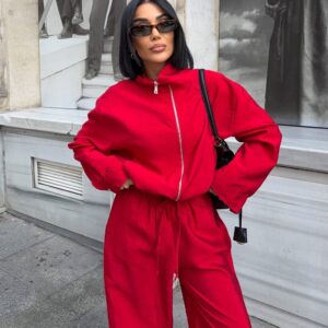 A red zip-up jacket and loose drawstring trousers are shown together from the front.