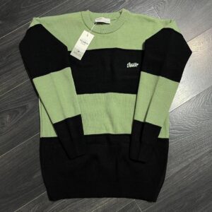 Front flat lay of a sage green and black color-block sweater with a ribbed crew neck and cuffs.