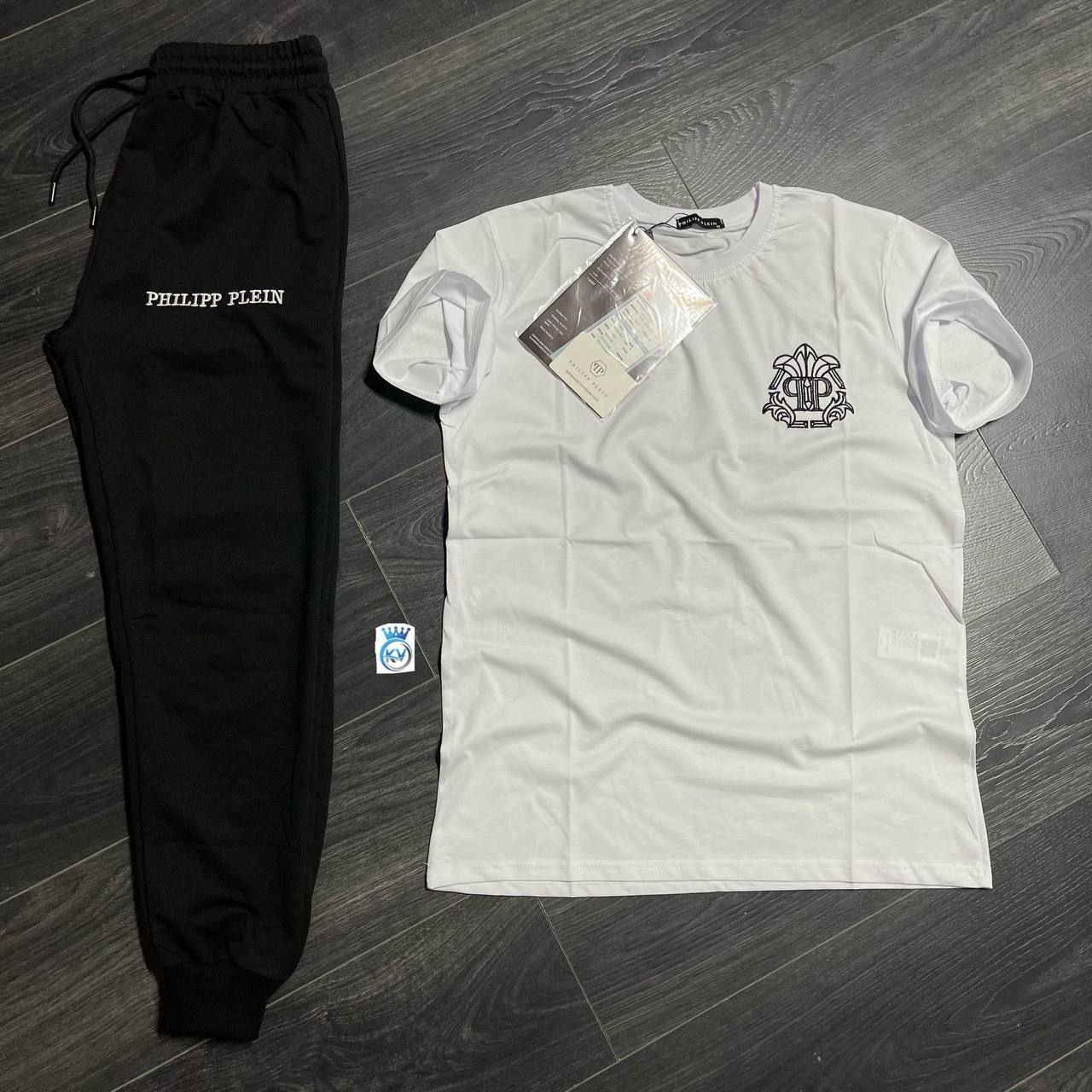 white-tee-jogger-set-4827 White crew-neck T-shirt with an ornate chest emblem displayed beside black drawstring joggers. available for wholesale in Turkey.