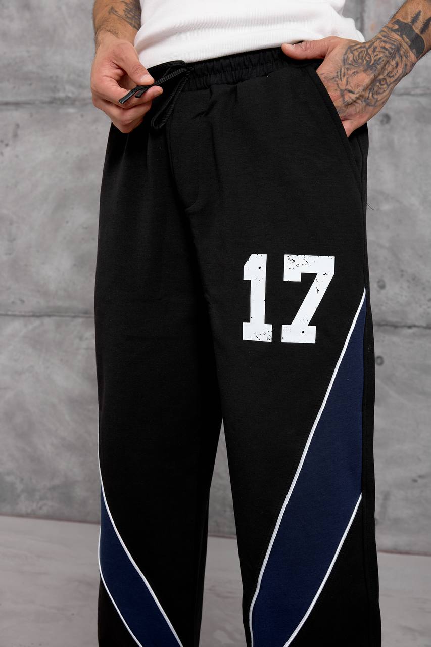 schwarz-jogginghose-taillenumfang-detail-4629 – Türkei Großhandel Nahansicht vorne mit elastischem Bund, schwarzem Kordelzug, abgenutztem weißen Nummer-17-Druck und marineblauem Seitenpaneel. - Türkei Großhandel