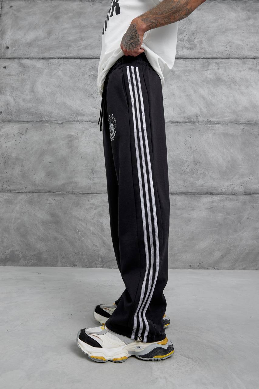 schwarz-doppelstrick-trackhose-profilstreifen-1483 – Großhandel Türkei Seitliche Profilansicht einer lockeren schwarzen Hose mit drei vertikalen silbernen Streifen von Taille bis Saum - Großhandel Türkei