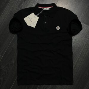 Front view of a black short-sleeve polo shirt with a button placket and small embroidered chest emblem. available for wholesale in Turkey.