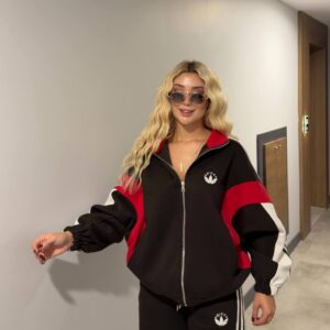 Model wearing a black zip-up track jacket with red and white color-block sleeves and matching striped trousers. available for wholesale in Turkey.
