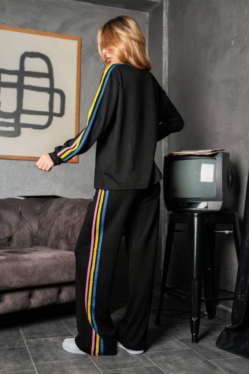 black-tracksuit-back-6258 Rear view of a black sweatshirt and wide-leg pants with pink, yellow, and turquoise stripes along the sleeves and legs.
