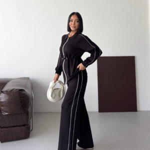Full view of a black zip-front tunic and wide-leg trousers with white piping and a cinched waist.