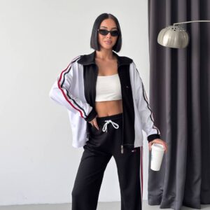 Front view of an open black and white track jacket with striped sleeves and black drawstring pants.