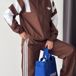 Close view of a brown high-collar zip jacket with elastic cuffs, white sleeve panels, and matching striped trousers.