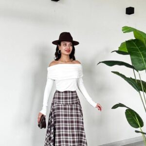 Front view of a brown plaid midi skirt with an asymmetric handkerchief hem and white off-shoulder top. available for wholesale in Turkey.