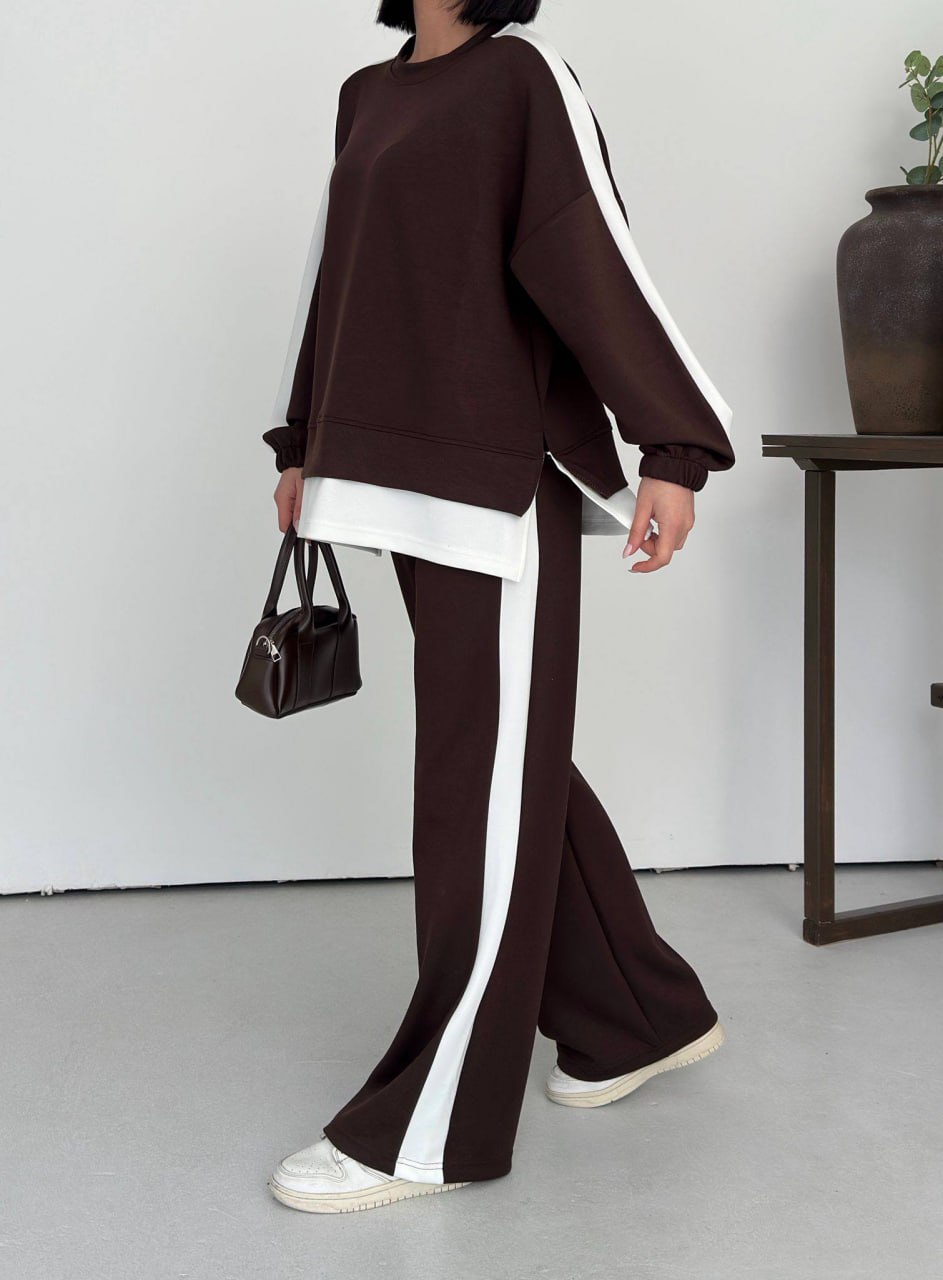 brown-tracksuit-side-detail-2658 Side view showing a dark brown sweatshirt with a white hem layer and matching wide-leg pants with a white stripe.