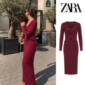 Burgundy two-piece knit outfit with a tie-front cardigan, fitted long skirt, pearl-like accents, and fringed hems.