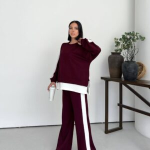 Front view of a burgundy sweatshirt and wide-leg pants with white side stripes and a layered hem.