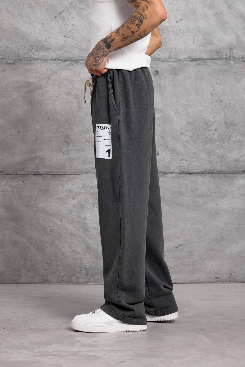 charcoal-wide-leg-sweatpants-side-6381 Side view of charcoal wide-leg sweatpants with a drawstring waist and white rectangular thigh patch. available for wholesale in Turkey.