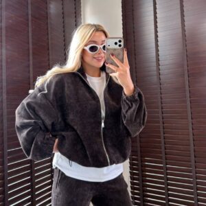 Front view of a dark oversized jacket with a silver zipper and gathered cuffs.