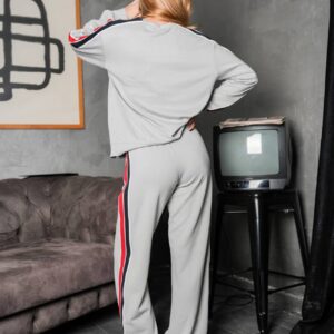 Back view of a light gray sweatshirt and matching pants with red and navy stripes running along the sleeves and legs.