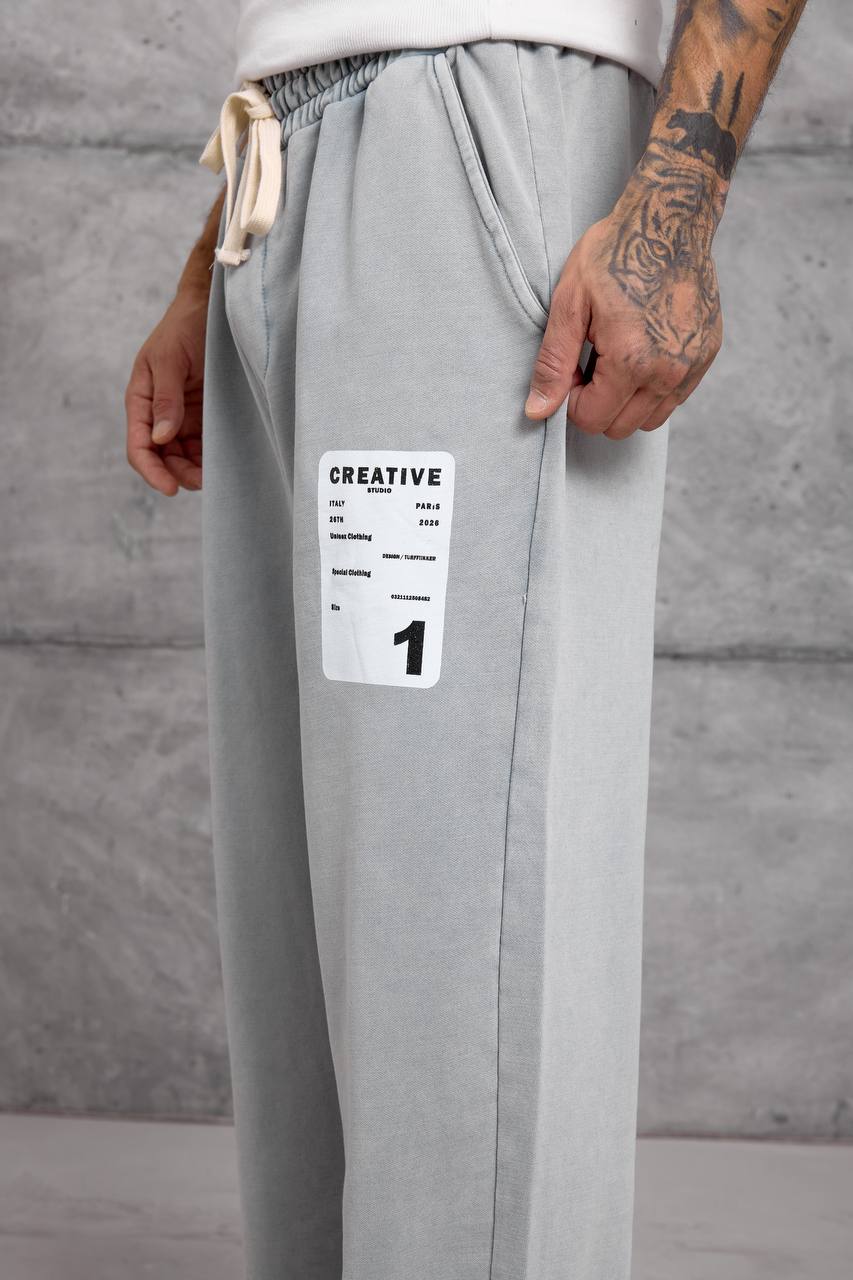 light-gray-patch-sweatpants-detail-7042 Close-up of a white rectangular graphic patch on light gray sweatpants beside a slanted pocket.