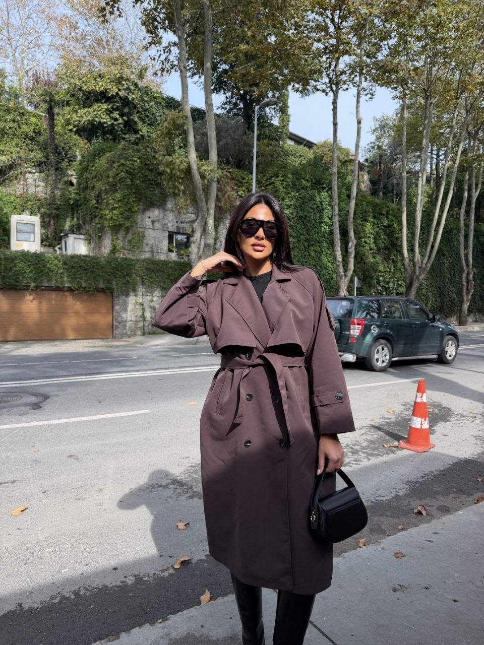 mauve-belted-trench-front-4827 Woman wearing a long mauve trench coat with wide lapels, black buttons, cuff straps, and a tied belt. available for wholesale in Turkey.