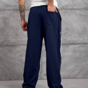 Vollständige Rückansicht der marineblauen, weiten Jogginghose mit elastischem Bund, einer einzigen Gesäßtasche und kontrastierenden Seitenpaneelen. - Türkei Großhandel