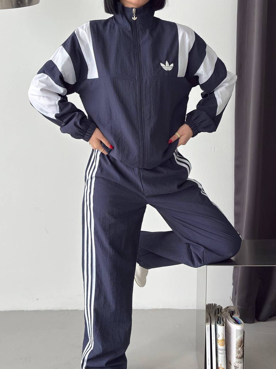 navy-tracksuit-closeup-6381 Navy zip-up jacket with a high collar, white sleeve panels, and matching wide-leg trousers with white side stripes. available for wholesale in Turkey.