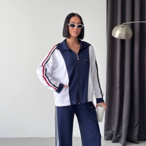 Vista frontal de una chaqueta azul marino con cremallera y mangas blancas, ribetes a rayas y pantalones anchos a juego - Mayorista turco.
