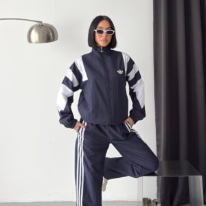 Model wearing a navy zip-up jacket and loose trousers with white panels and side stripes. available for wholesale in Turkey.