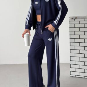 Marineblaue Reißverschlussjacke und passende Hose mit weißen Arm- und Seitenstreifen, dazu ein koordiniertes Crop-Top.